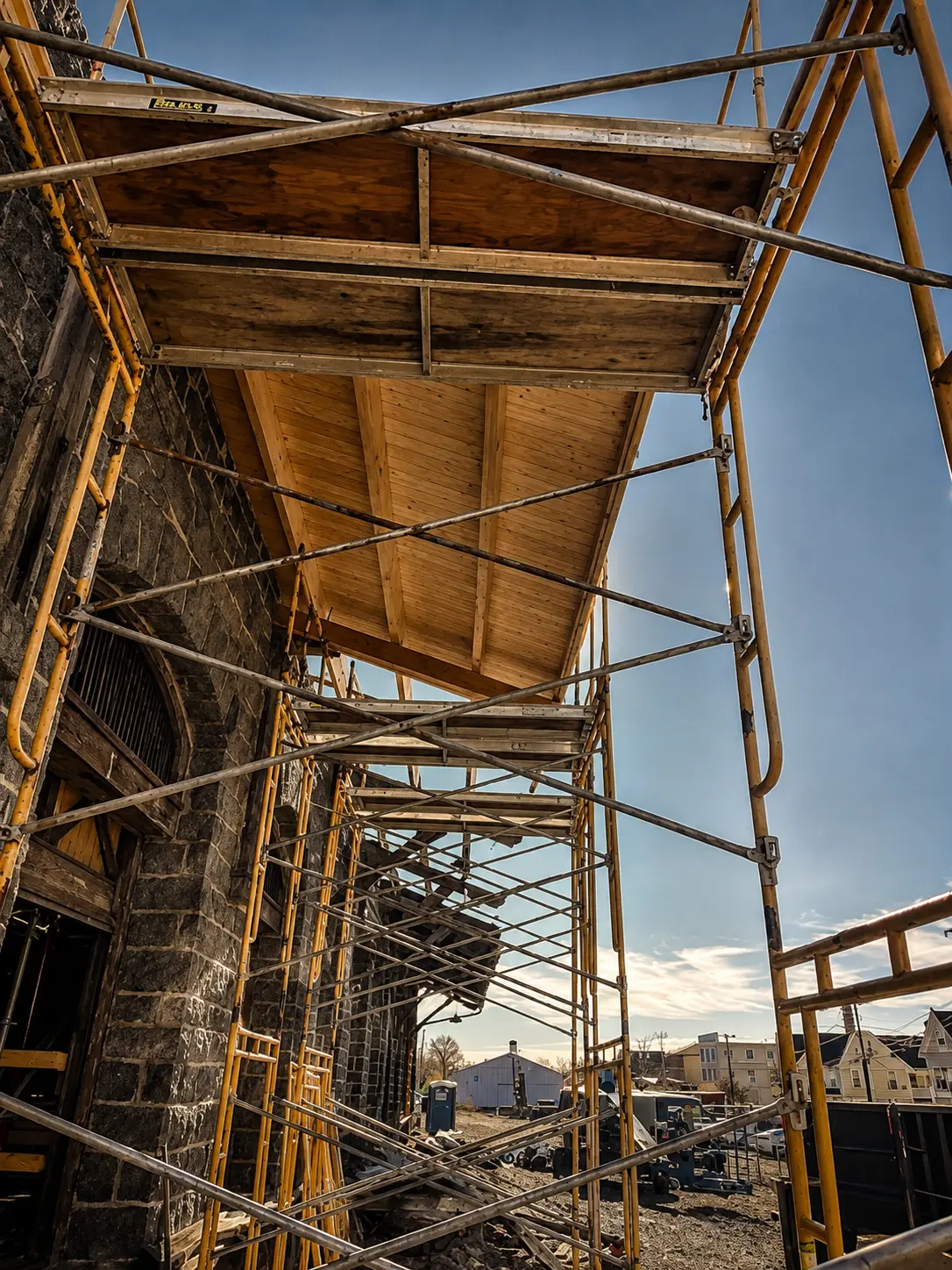 Yellow scaffolding standing against the stone wall of the freight house during Phase I stabilization