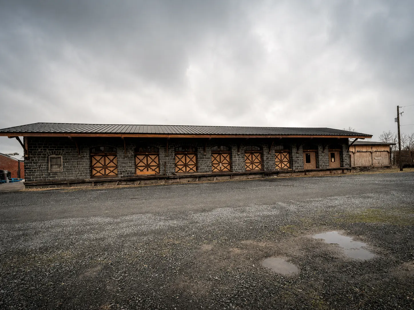 The 1902 Quakertown Freight House seen along its Front Street elevation, a run of eight timber freight doors under a dark standing-seam roof