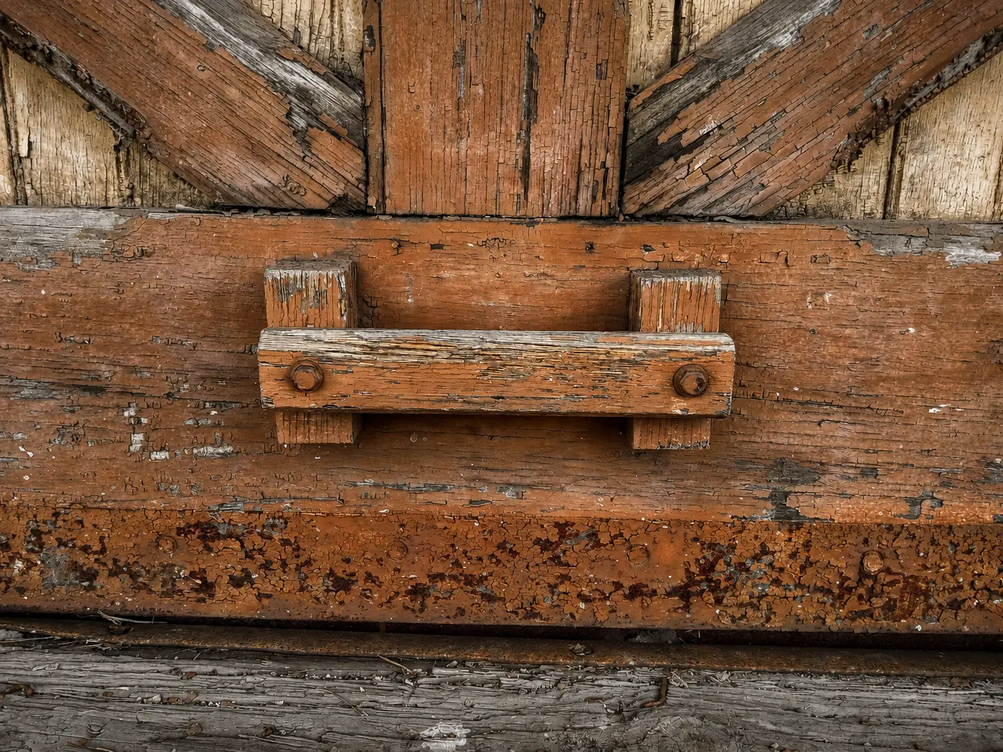 Close detail of weathered orange-painted boards and iron hardware on an original freight door